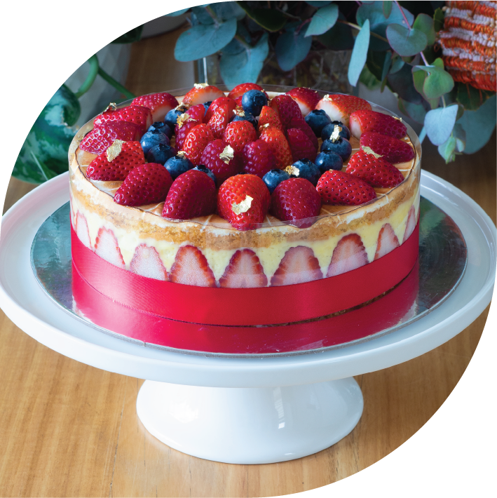 a fraisier cake with visible strawberries and pastry cream on a white cake stand