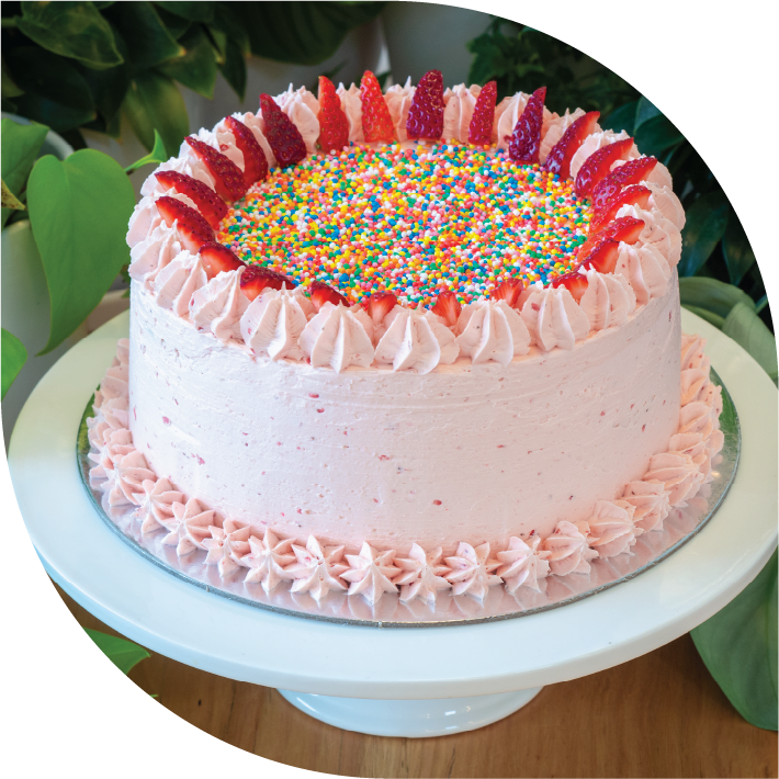 a pink strawberry cake decorated with 100s & 1000s and fresh strawberries