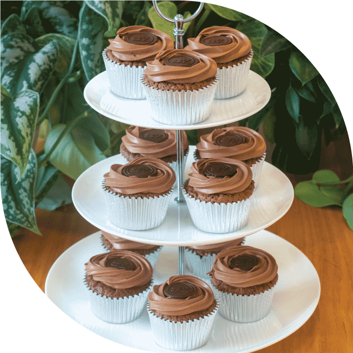 a white three tiered high tea stand with 12 dark chocolate Sachertorte-inspired cupcakes decorated with dark chocolate buttons