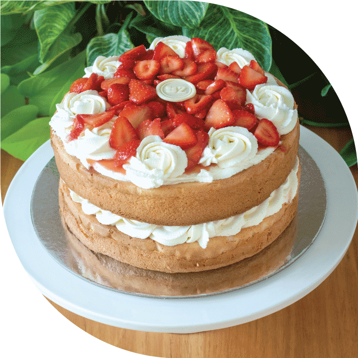 a victoria sponge filled with cream and decorated with glazed strawberries and cream rosettes